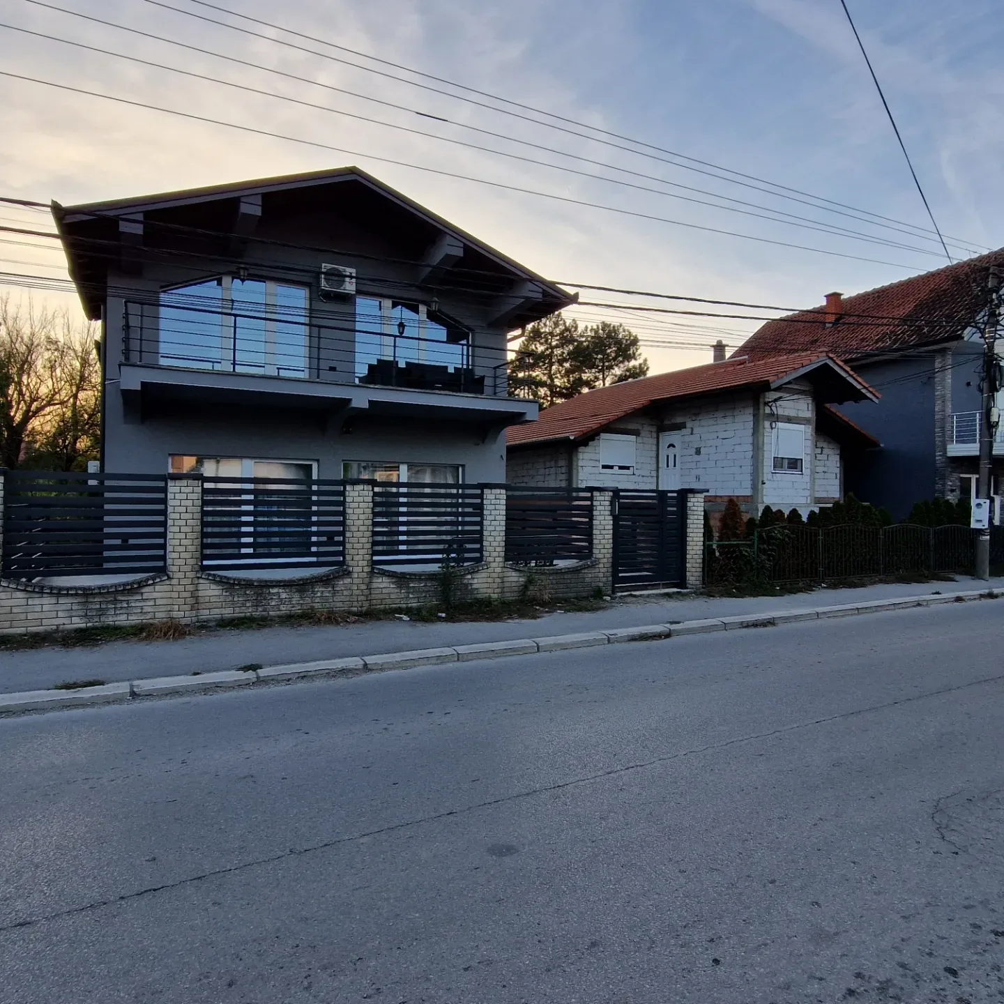 Kapija sa lamelama i prateća ograda, snimljene sa ulice u sumrak